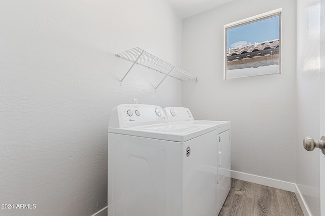 clothes washing area featuring washer and clothes dryer and hardwood / wood-style flooring