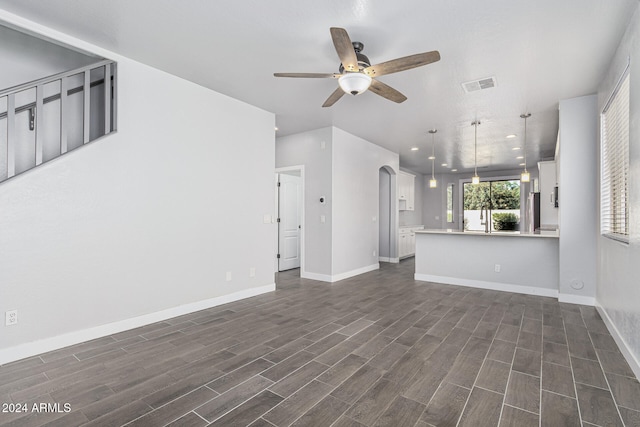 unfurnished living room with ceiling fan and dark hardwood / wood-style flooring