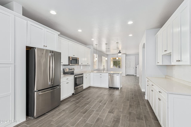 kitchen featuring appliances with stainless steel finishes, sink, pendant lighting, white cabinets, and dark hardwood / wood-style floors