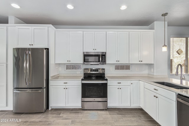 kitchen with white cabinets, appliances with stainless steel finishes, pendant lighting, and sink