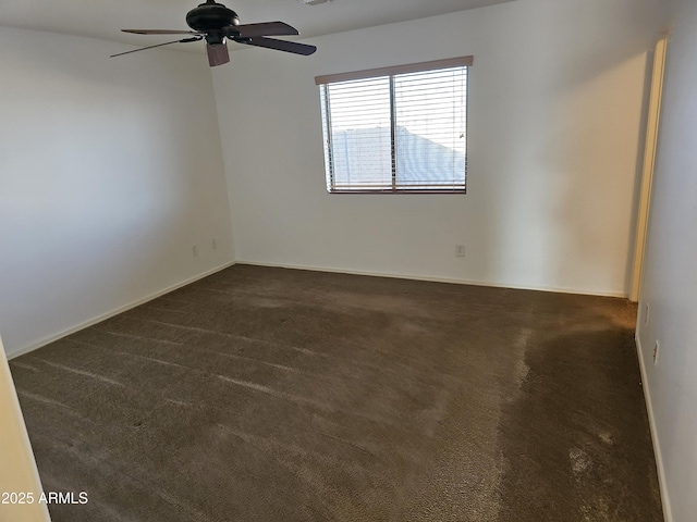 empty room with ceiling fan and dark colored carpet