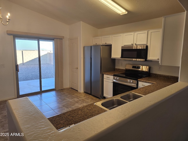 kitchen with a notable chandelier, lofted ceiling, white cabinetry, appliances with stainless steel finishes, and sink