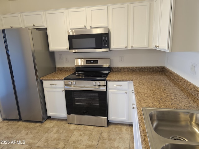 kitchen with stainless steel appliances, light tile patterned flooring, white cabinets, and sink