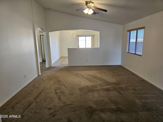 empty room with ceiling fan with notable chandelier, plenty of natural light, and light colored carpet