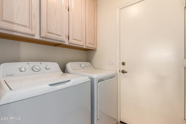 washroom with washer and dryer and cabinets