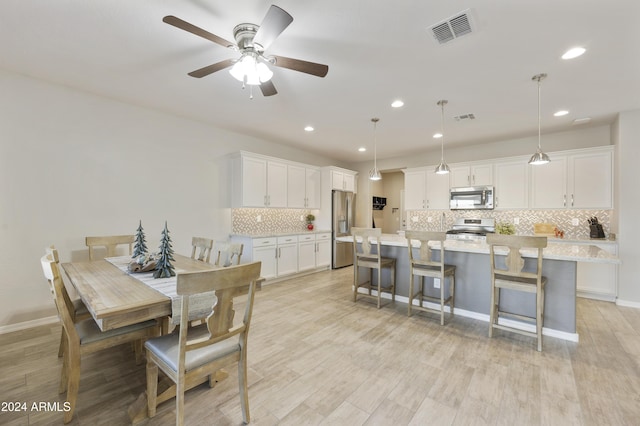 dining area with light hardwood / wood-style floors and ceiling fan