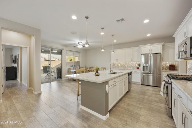 kitchen with white cabinets, ceiling fan, stainless steel appliances, and a kitchen island with sink