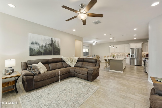 living room featuring light hardwood / wood-style floors, ceiling fan, and sink