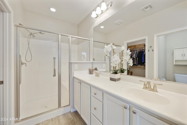 bathroom featuring wood-type flooring, vanity, toilet, and a shower with shower door