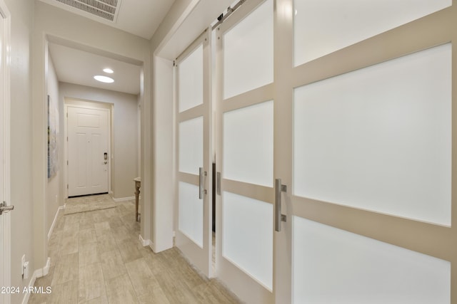 hall featuring a barn door and light hardwood / wood-style flooring