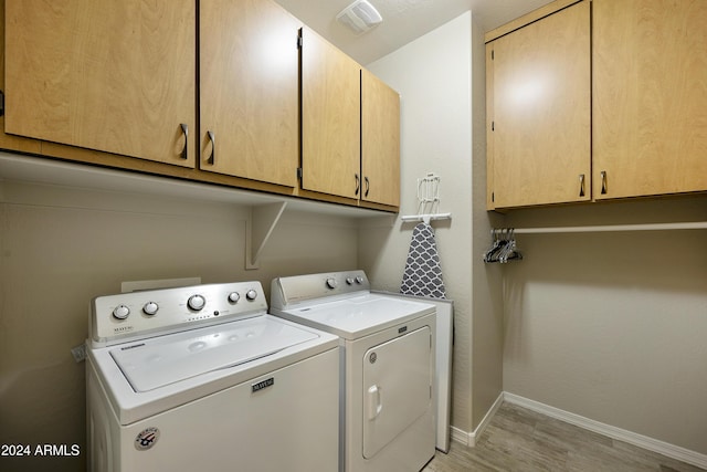 washroom with cabinets, light hardwood / wood-style flooring, and washer and dryer