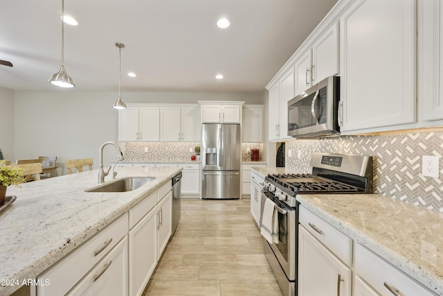 kitchen featuring decorative light fixtures, sink, light stone countertops, and stainless steel appliances