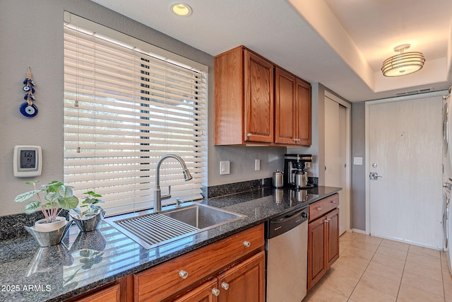 kitchen featuring light tile patterned flooring, stainless steel dishwasher, sink, and dark stone countertops