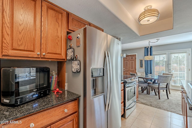 kitchen featuring light tile patterned flooring, dark stone counters, hanging light fixtures, stainless steel appliances, and a textured ceiling