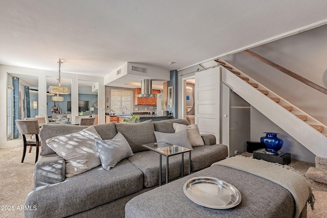 living room featuring sink, a barn door, and carpet flooring