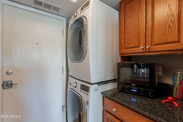 laundry room with stacked washer / dryer and cabinets