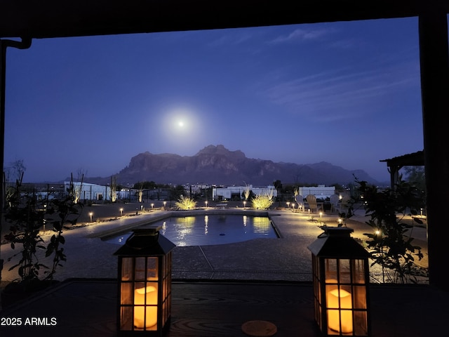 pool at dusk featuring a patio and a mountain view