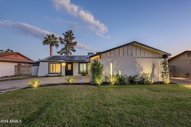 view of front of property with a front yard and solar panels