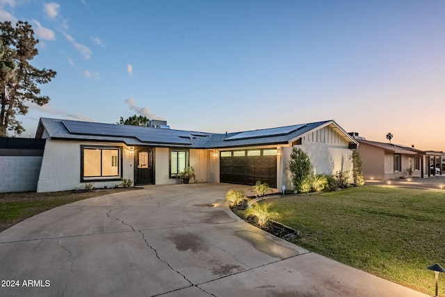 ranch-style house featuring solar panels, a yard, and a garage