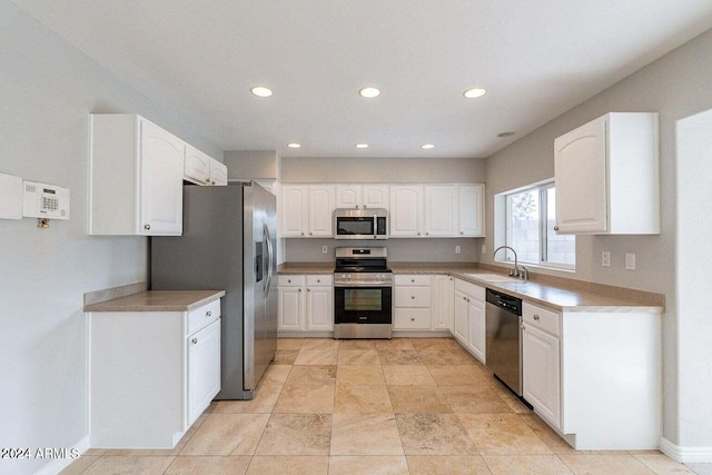 kitchen with appliances with stainless steel finishes, white cabinetry, and sink