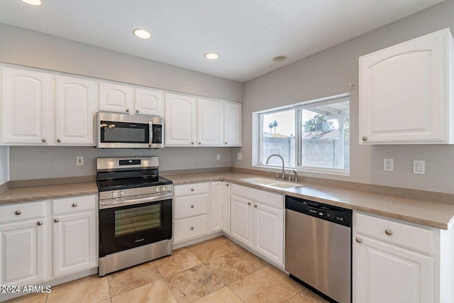 kitchen with sink, white cabinetry, stainless steel appliances, and light tile patterned floors