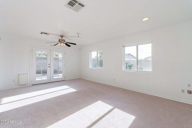 carpeted spare room featuring a wealth of natural light, french doors, and ceiling fan