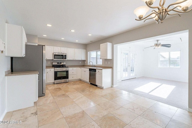 kitchen with plenty of natural light, light colored carpet, white cabinetry, and appliances with stainless steel finishes