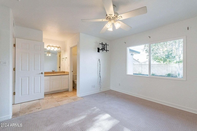 interior space with light tile patterned floors, ensuite bath, and ceiling fan