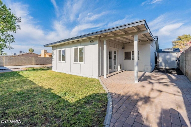 back of property with a patio area, a yard, and french doors