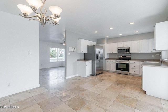 kitchen featuring ceiling fan with notable chandelier, stainless steel appliances, sink, white cabinets, and hanging light fixtures