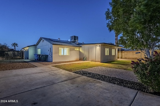 back house at dusk with a lawn and cooling unit