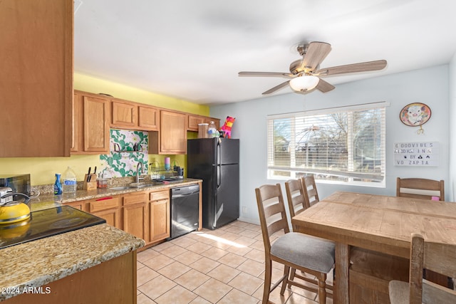 kitchen featuring black appliances, sink, ceiling fan, light tile patterned flooring, and light stone counters