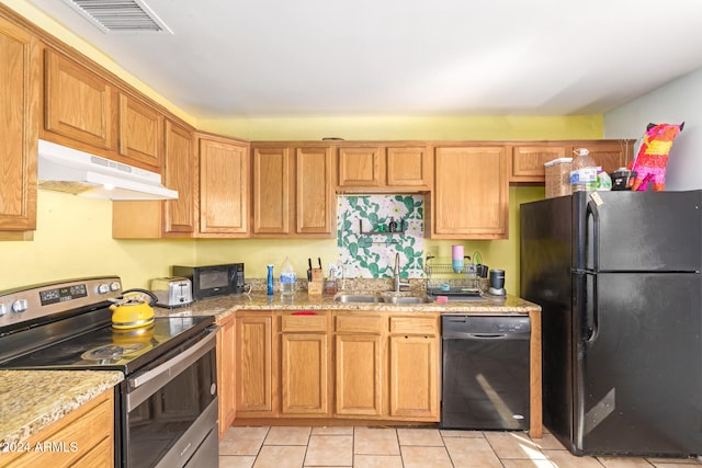 kitchen with light stone counters, sink, light tile patterned floors, and black appliances