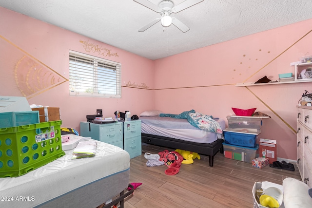 bedroom featuring ceiling fan, a textured ceiling, and light wood-type flooring