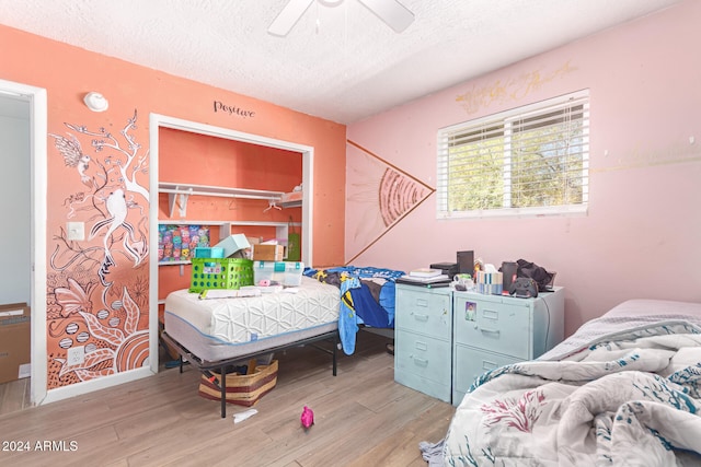 bedroom with a textured ceiling, a closet, light hardwood / wood-style flooring, and ceiling fan