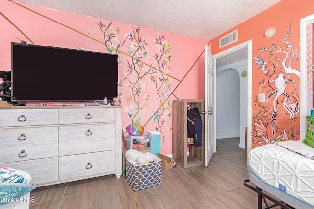 bedroom with hardwood / wood-style floors and a textured ceiling