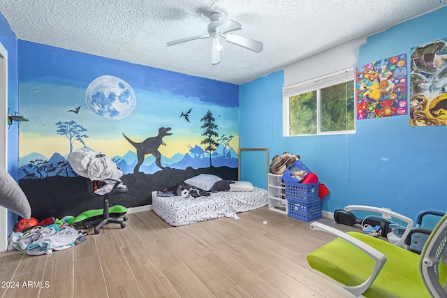 bedroom with hardwood / wood-style flooring, ceiling fan, and a textured ceiling