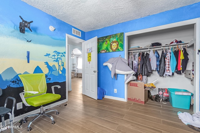 interior space with wood-type flooring, a textured ceiling, and a closet