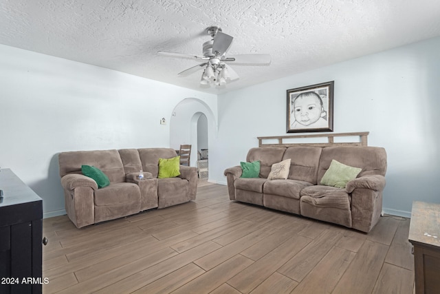 living room with a textured ceiling, light hardwood / wood-style flooring, and ceiling fan