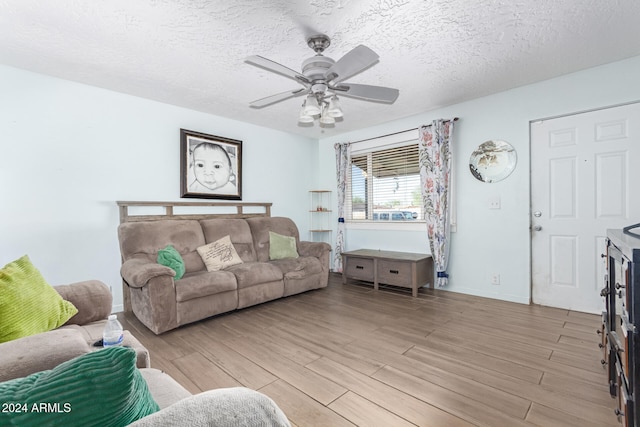 living room featuring a textured ceiling, light wood-type flooring, and ceiling fan