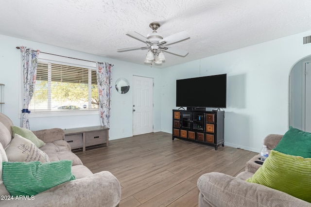 living room with hardwood / wood-style floors, ceiling fan, and a textured ceiling