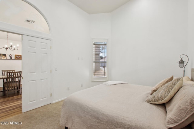 carpeted bedroom with a towering ceiling and a chandelier