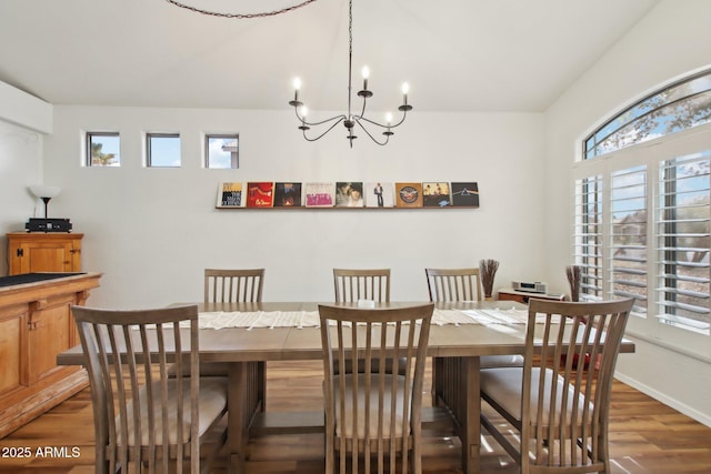 dining space with dark wood-type flooring and an inviting chandelier