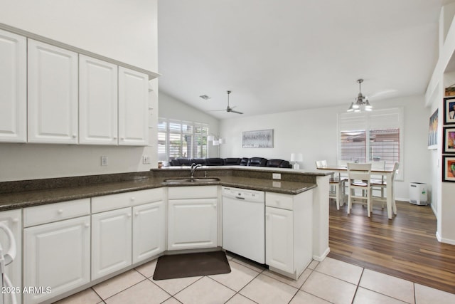 kitchen with light tile patterned floors, sink, dishwasher, white cabinets, and kitchen peninsula