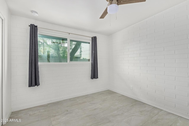 spare room with ceiling fan and brick wall