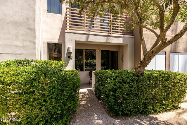 property entrance with a balcony and stucco siding