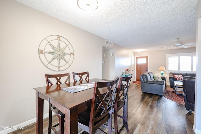 dining room featuring ceiling fan, dark wood-type flooring, and a textured ceiling