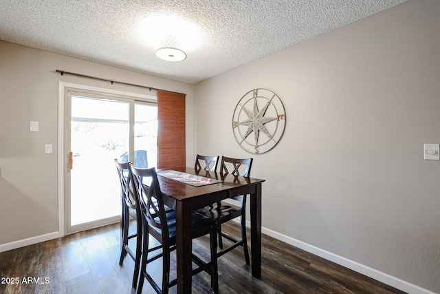 dining space featuring dark wood-type flooring and a textured ceiling