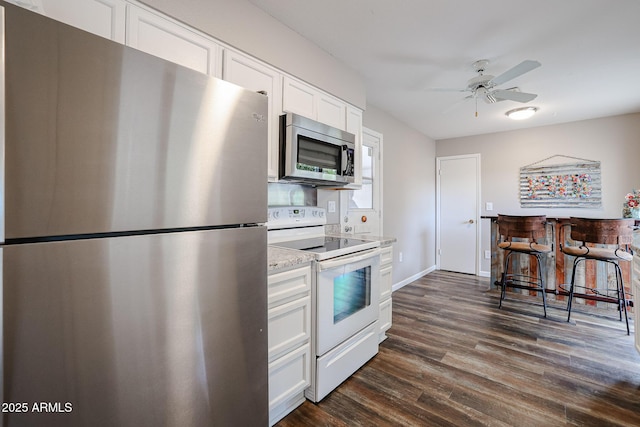 kitchen featuring white cabinets, ceiling fan, dark hardwood / wood-style floors, appliances with stainless steel finishes, and light stone counters