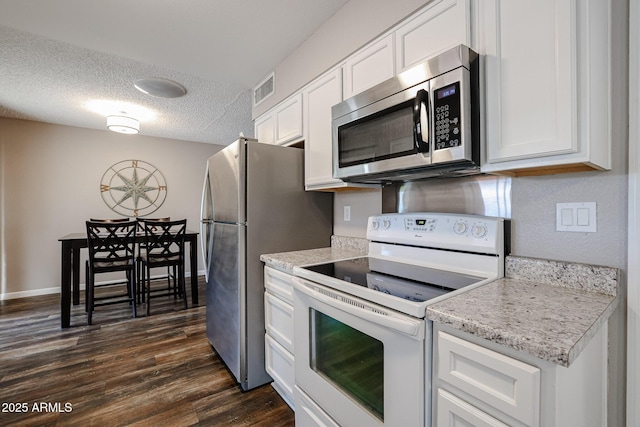 kitchen with white cabinetry, dark wood-type flooring, stainless steel appliances, light stone counters, and a textured ceiling